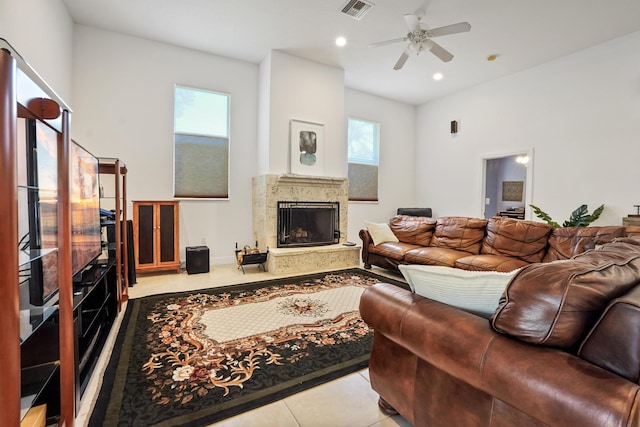 tiled living room with ceiling fan and a premium fireplace