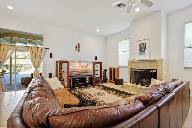 tiled living room with ceiling fan and a fireplace