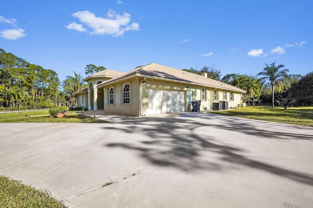 view of front of property with a front lawn, central AC unit, and a garage