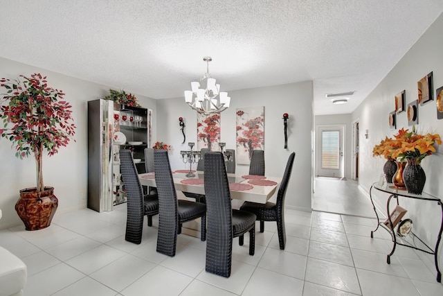 dining space featuring a chandelier, a textured ceiling, and light tile patterned flooring