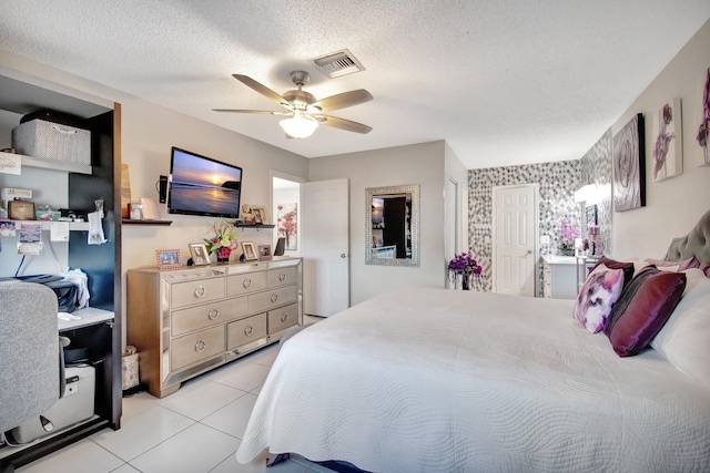 tiled bedroom with ceiling fan and a textured ceiling