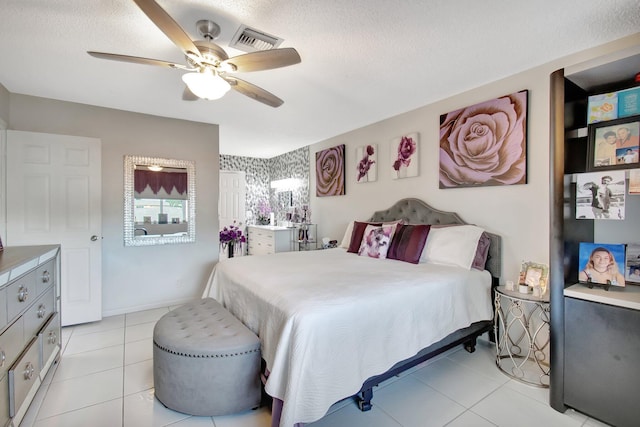 bedroom with ceiling fan, light tile patterned floors, and a textured ceiling