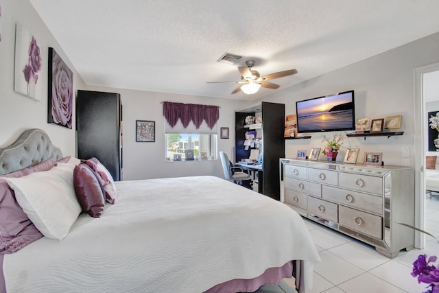 tiled bedroom with ceiling fan and a textured ceiling