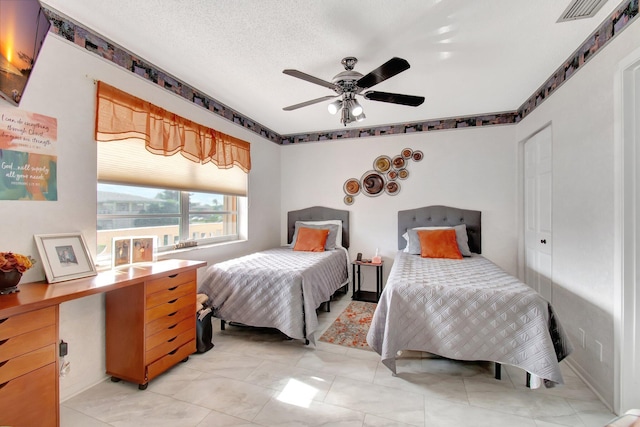 bedroom with ceiling fan and a textured ceiling