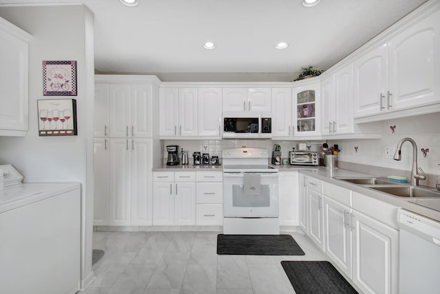 kitchen with white appliances, sink, tasteful backsplash, washer / dryer, and white cabinetry