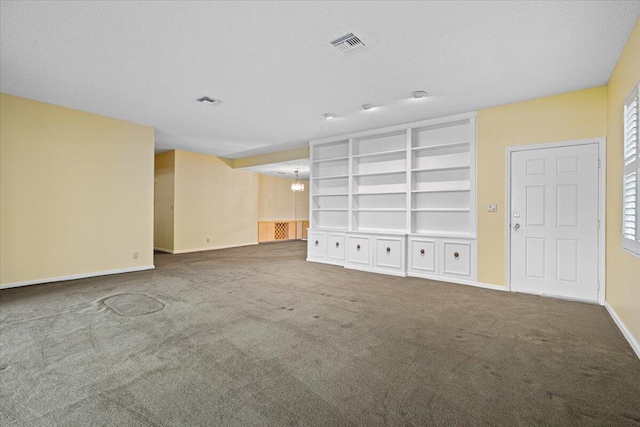 unfurnished living room with carpet, a textured ceiling, built in features, and a notable chandelier