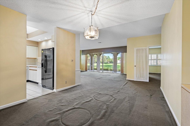 interior space featuring light colored carpet, a textured ceiling, and an inviting chandelier