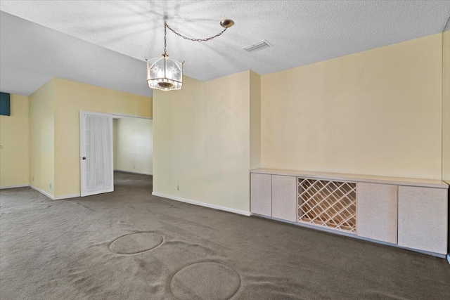 carpeted empty room featuring a chandelier and a textured ceiling