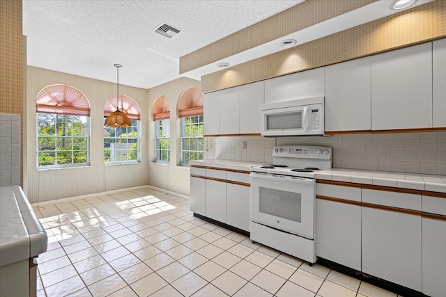 kitchen with white cabinets, pendant lighting, and white appliances