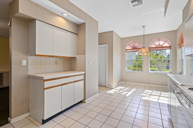 kitchen featuring decorative light fixtures, stove, white cabinetry, and light tile patterned floors