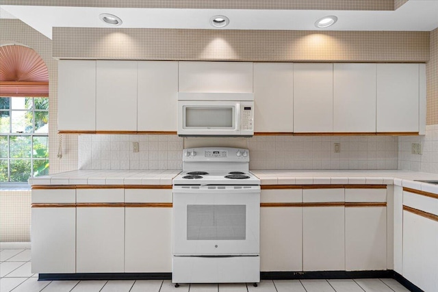 kitchen with backsplash, white cabinets, and white appliances