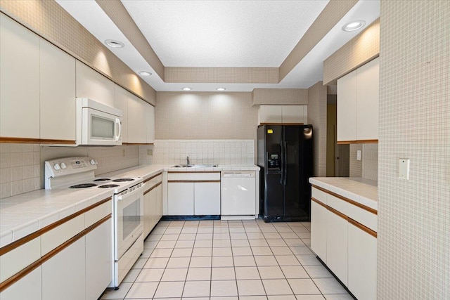 kitchen with white cabinetry, sink, white appliances, decorative backsplash, and light tile patterned flooring