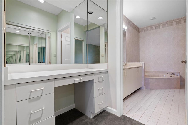 bathroom with tile patterned floors, vanity, and tiled bath