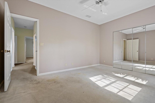 unfurnished bedroom with ceiling fan, a closet, and light carpet