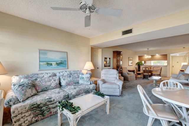 carpeted living room featuring ceiling fan and a textured ceiling