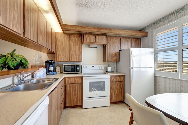 kitchen featuring a textured ceiling, white appliances, and sink