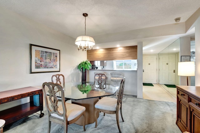 dining room with light colored carpet, a textured ceiling, and an inviting chandelier