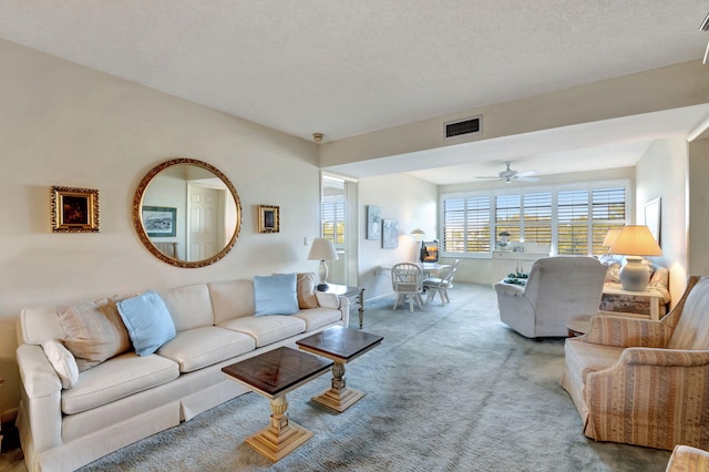 living room with carpet flooring, ceiling fan, and a textured ceiling