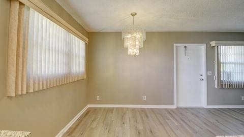 spare room featuring a wealth of natural light, hardwood / wood-style floors, and a notable chandelier