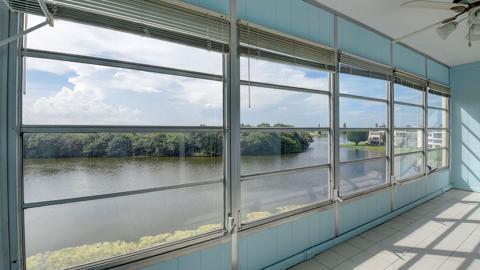 unfurnished sunroom featuring a water view and ceiling fan