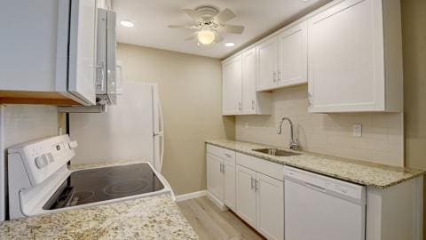 kitchen featuring sink, light wood-type flooring, white appliances, light stone countertops, and white cabinets