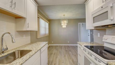 kitchen with pendant lighting, sink, white appliances, white cabinets, and light wood-type flooring