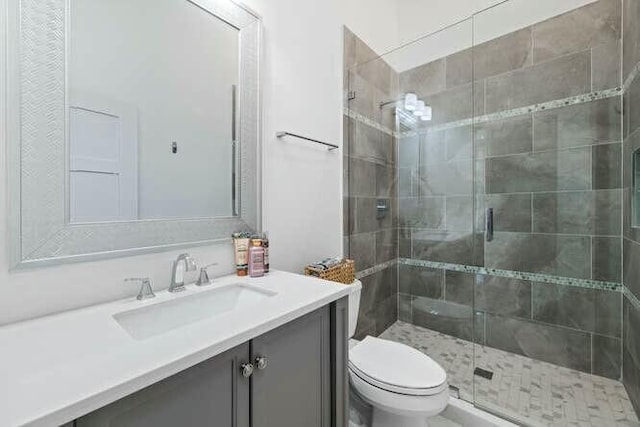 bathroom with an enclosed shower, vanity, and toilet