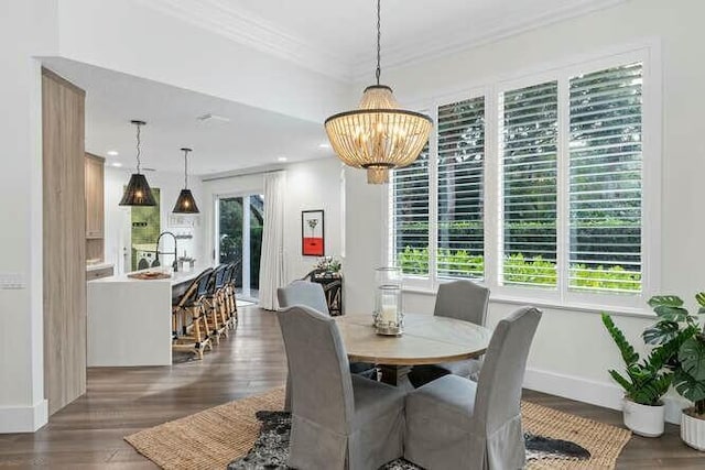 dining area with dark wood-type flooring, ornamental molding, a healthy amount of sunlight, and an inviting chandelier