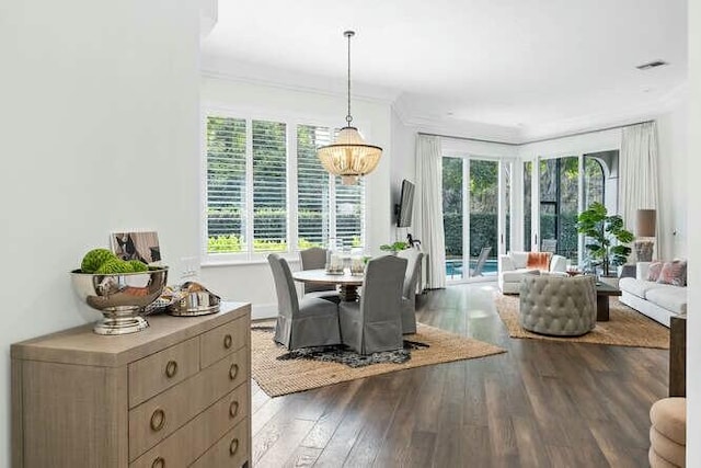 dining area with ornamental molding, dark wood-type flooring, and a chandelier