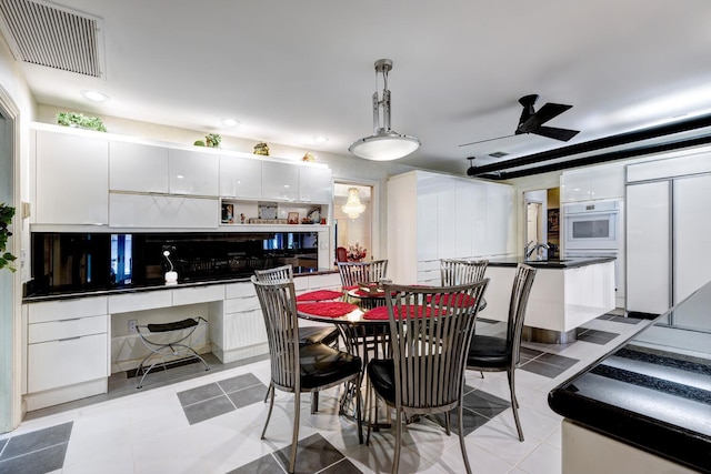 tiled dining space with ceiling fan and sink