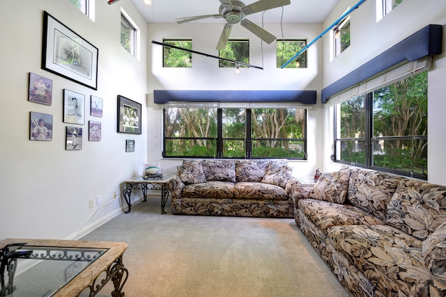 carpeted living room with ceiling fan and a high ceiling