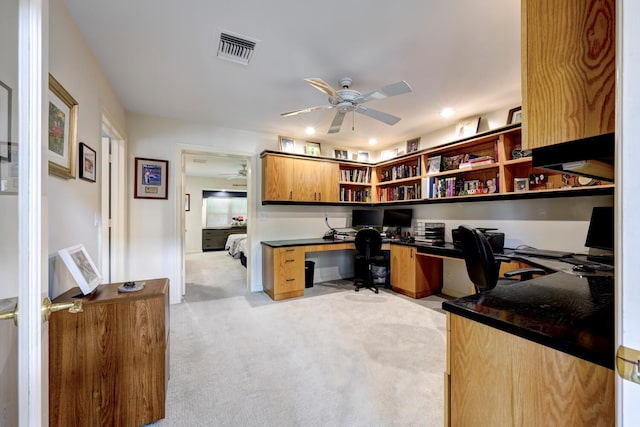 carpeted office featuring ceiling fan and built in desk