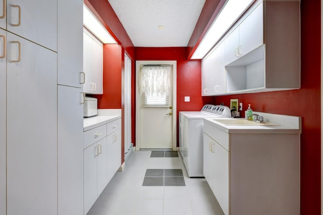 clothes washing area featuring washer and clothes dryer, sink, a textured ceiling, and cabinets