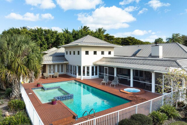 back of property featuring a swimming pool with hot tub, a patio area, and a sunroom