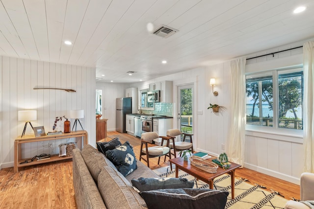 living room featuring wooden ceiling, light hardwood / wood-style flooring, and a healthy amount of sunlight