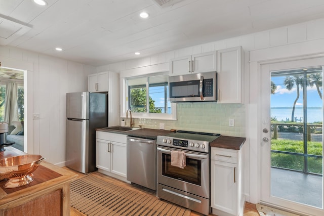 kitchen with white cabinets, decorative backsplash, sink, and stainless steel appliances