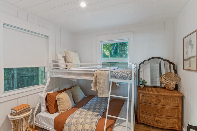 bedroom with hardwood / wood-style flooring and wood walls