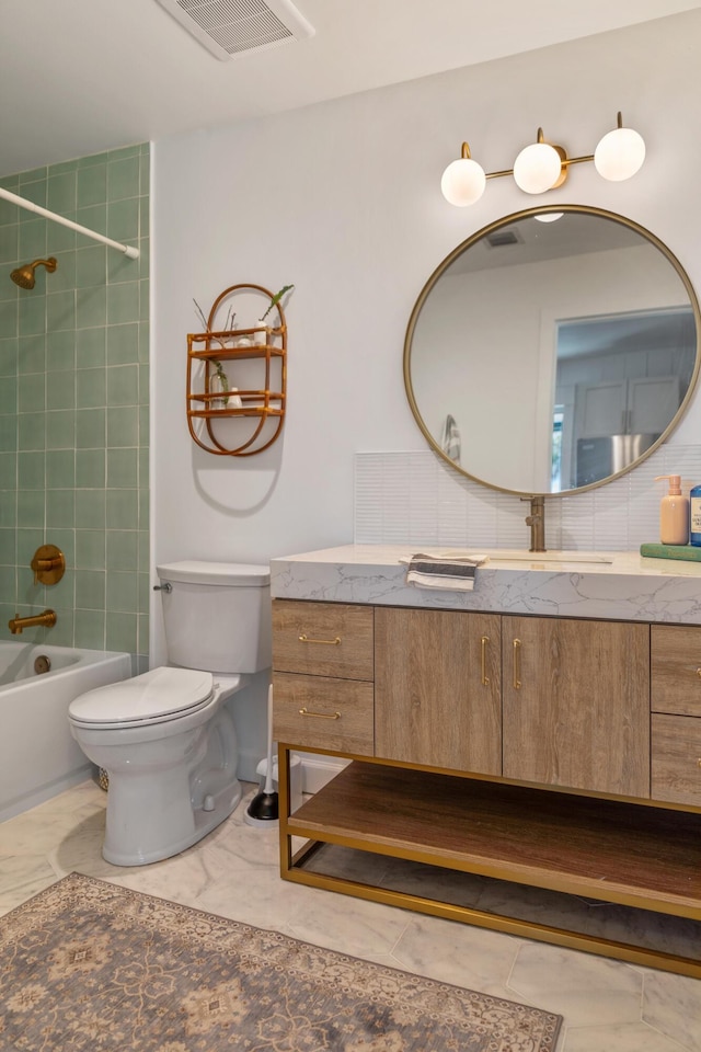 full bathroom with toilet, vanity, and tiled shower / bath