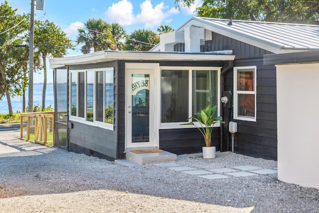 view of side of home with a sunroom and a water view