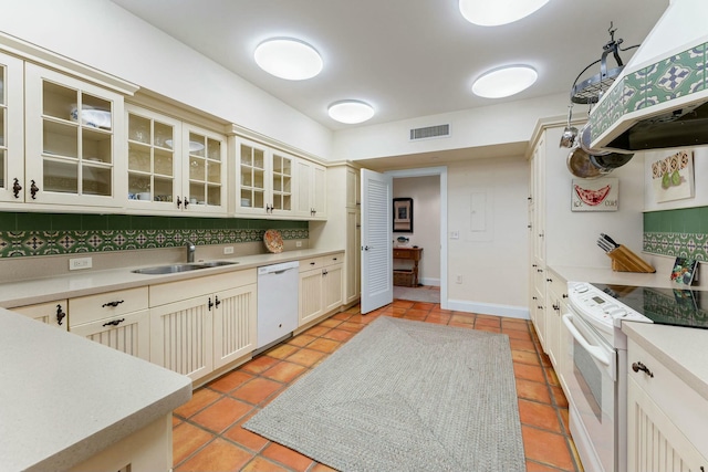 kitchen featuring exhaust hood, tasteful backsplash, white appliances, cream cabinets, and sink