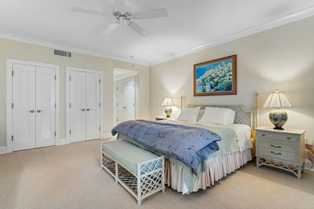 bedroom with ceiling fan, carpet floors, ornamental molding, and multiple closets