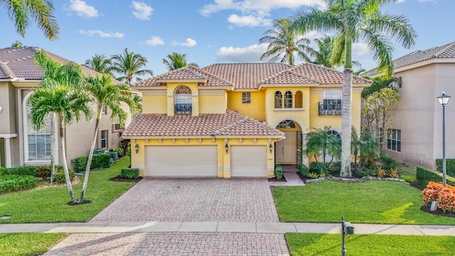 mediterranean / spanish home featuring a garage and a front yard