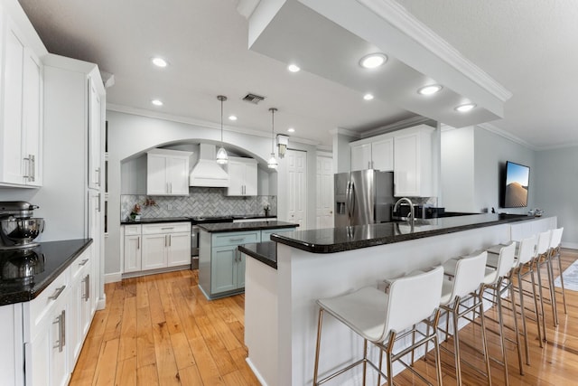 kitchen with custom exhaust hood, appliances with stainless steel finishes, a kitchen breakfast bar, hanging light fixtures, and white cabinets