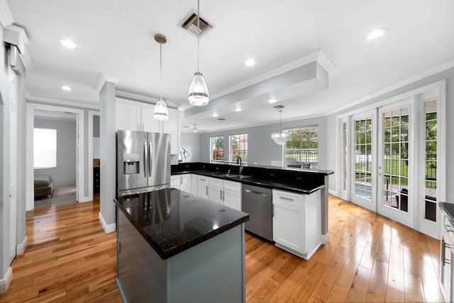 kitchen featuring pendant lighting, white cabinets, stainless steel appliances, ornamental molding, and kitchen peninsula