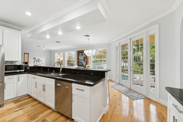 kitchen featuring white cabinetry, appliances with stainless steel finishes, dark stone countertops, pendant lighting, and sink