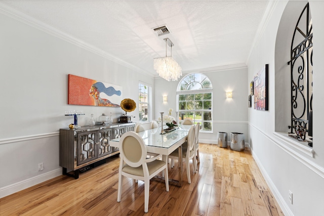 dining area featuring an inviting chandelier, crown molding, and light hardwood / wood-style floors