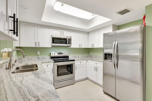 kitchen with white cabinetry, sink, light stone counters, and appliances with stainless steel finishes