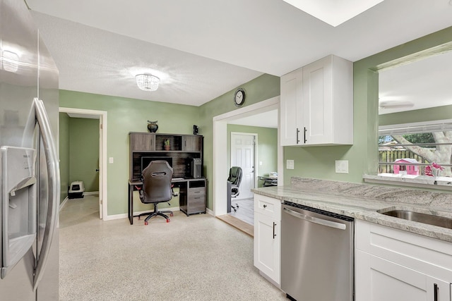 kitchen with light stone counters, stainless steel appliances, sink, and white cabinets