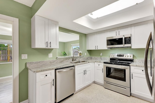 kitchen featuring light stone counters, stainless steel appliances, sink, and white cabinets