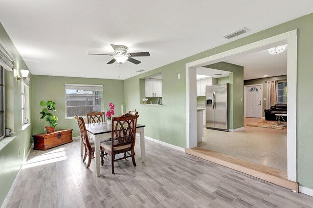 dining area with ceiling fan, a wealth of natural light, and light hardwood / wood-style flooring